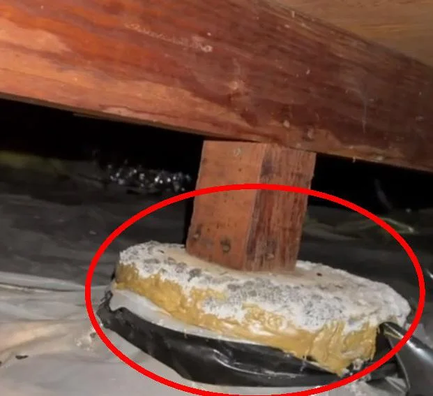 Concrete crawlspace support pier with repair material and white efflorescence below a wood post