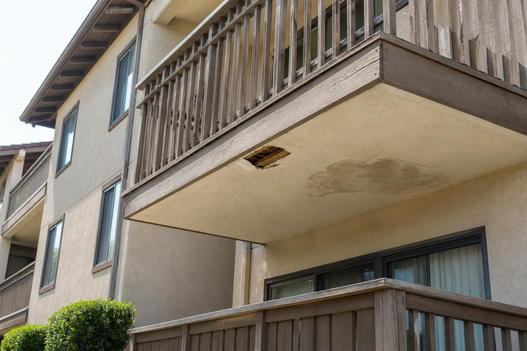 Water-stained balcony soffit with a small opening exposing wood joists