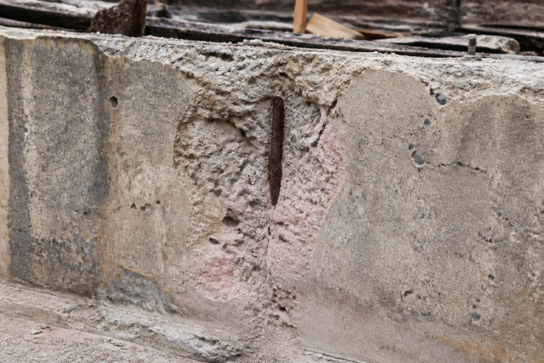 Fire-exposed concrete stem wall with spalling, discoloration, and exposed reinforcement